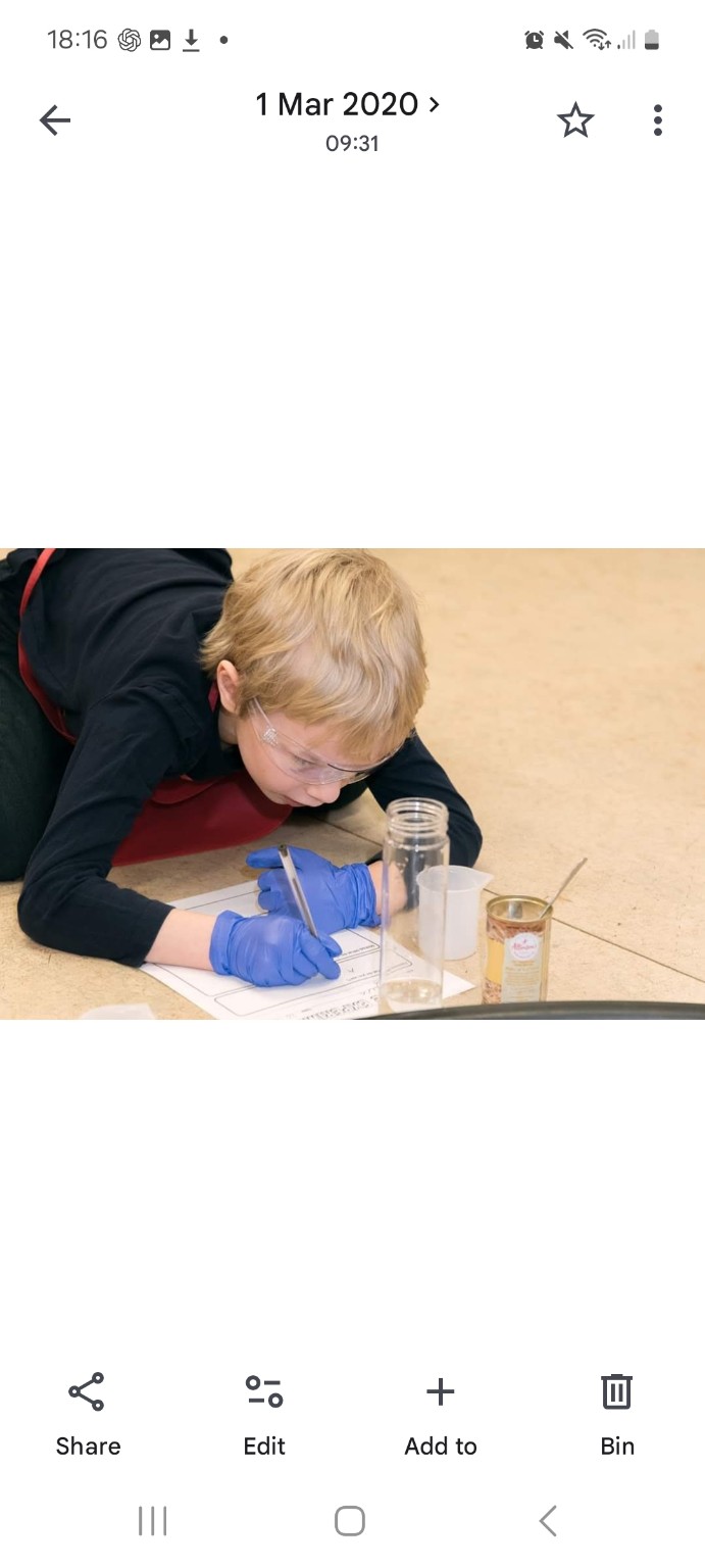 A young scientist wearing goggles and gloves records findings during an investigation