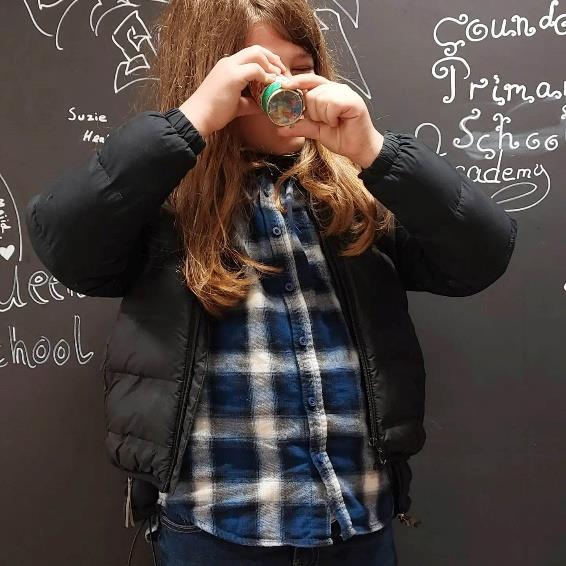 A pupil looking through a kaleidoscope made during a light workshop